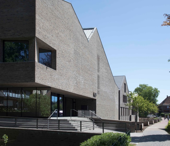 Zu sehen ist die graue Klinkerfassade des kult Westmünsterland in Vreden. Vor dem Gebäude befindet sich ein Wassergraben sowie ein Grünstreifen.