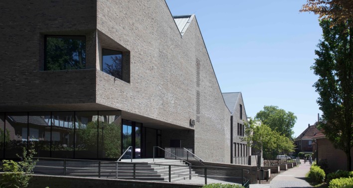 Zu sehen ist die graue Klinkerfassade des kult Westmünsterland in Vreden. Vor dem Gebäude befindet sich ein Wassergraben sowie ein Grünstreifen.