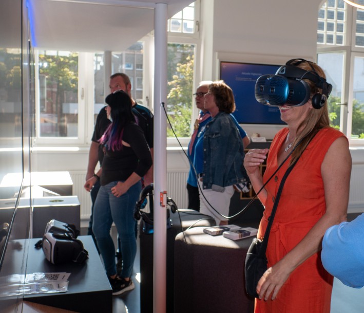 Menschen mit 3D-Brillen vor Museumsvitrine 
