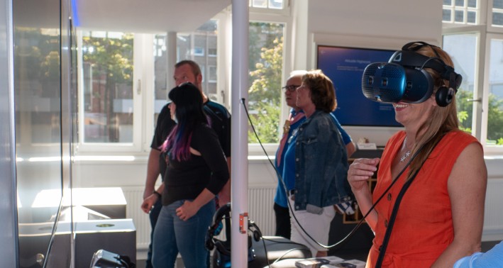 Menschen mit 3D-Brillen vor Museumsvitrine