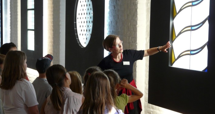 Frau zeigt Kindern Glasmalerei