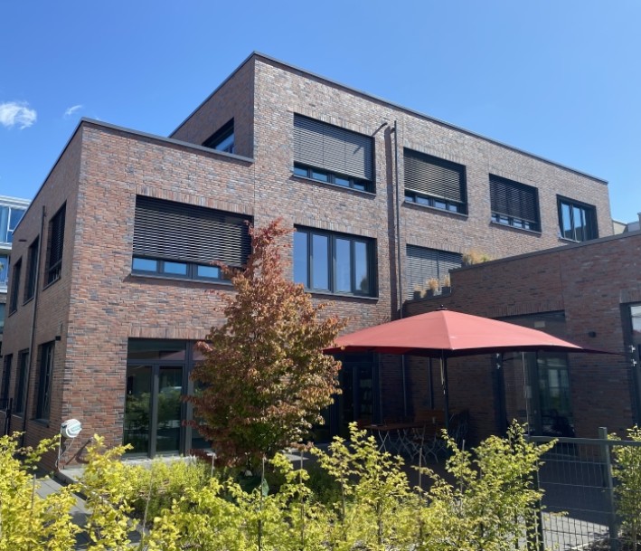 Haus mit Terrasse, Sonnenschirm und Grün