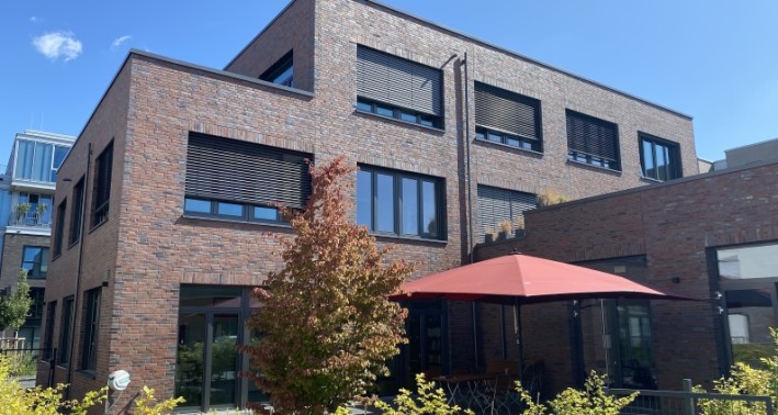 Haus mit Terrasse, Sonnenschirm und Grün