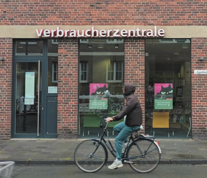 Das Foto zeigt einen Fahrradfahrer vor dem Gebäude der Verbaucherzentrale.