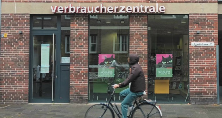 Das Foto zeigt einen Fahrradfahrer vor dem Gebäude der Verbaucherzentrale.
