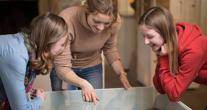 Drei Menschen schauen ein Modell in einen Glaskasten an