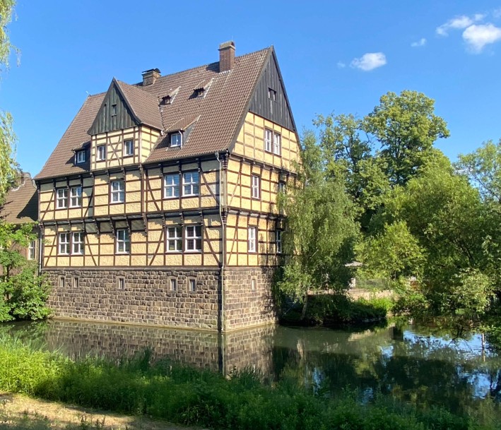 Fachwerkhaus, umgeben von Wasser und Bäumen. In diesem Gebäude befindet sich das Museum der Stadt Gladbeck.