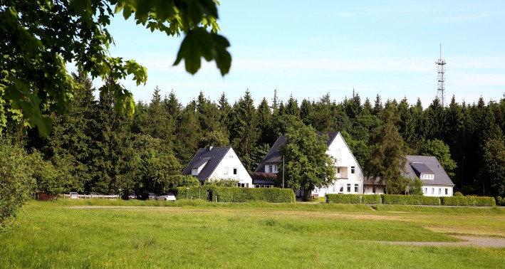 Das Bild zeigt eine Gruppe von Häusern vor einem Waldstück