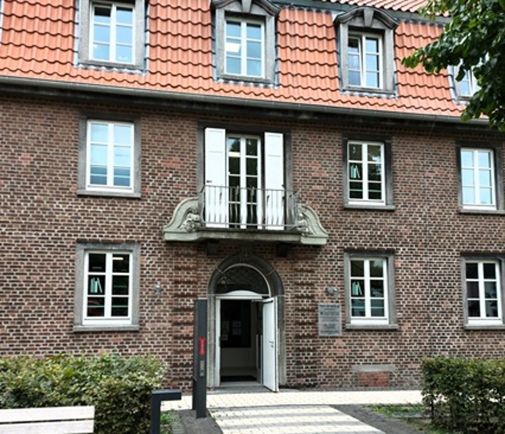 Die Stadtbibliothek im Haus der Bildung: historische Hausfasade im städtischen Grün