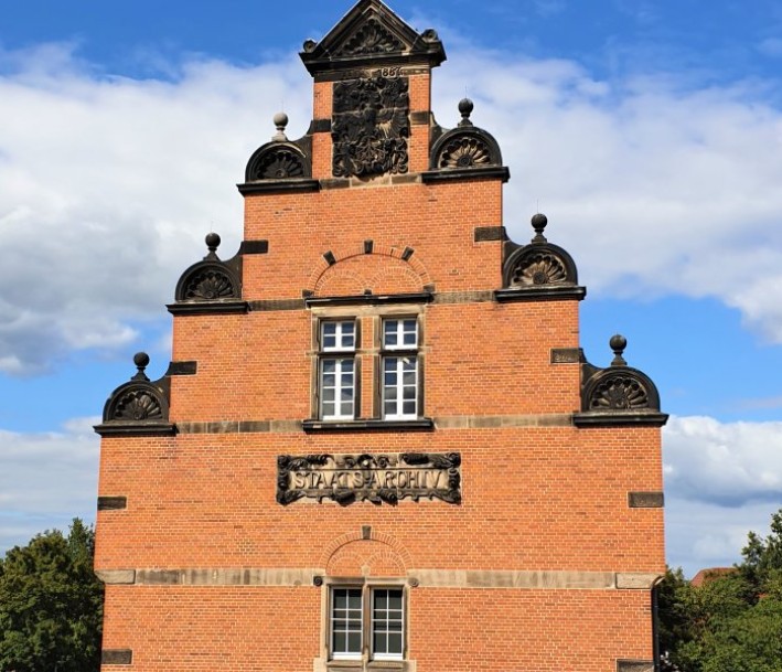 Das Bild zeigt ein rotes Backsteingebäude mit der Aufschrift 