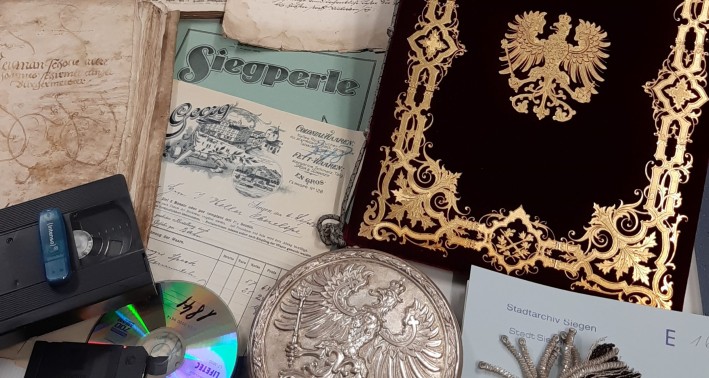 EIn Bild von verschiedenen Archivalien, darunter: CDs, Urkunden, Medaillon