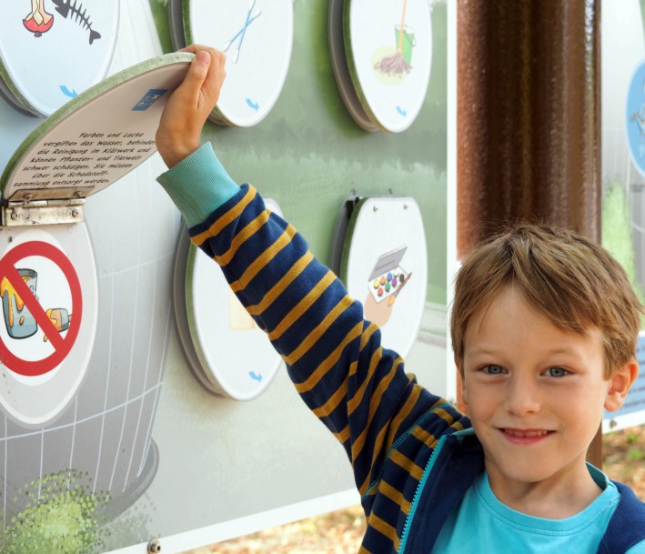 Ein Kind, das Lernkarten am Klärwerk des Lernorts Wasserschule in Köln in der Hand hält. 