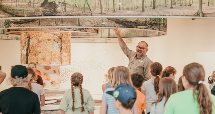 EIn Guide erklärt einer Gruppe von Schüler*innen etwas anhand eines Ausstellungsobjekts