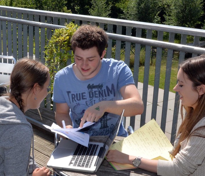 Das Bild zeigt eine Gruppe von Schülern arbeitend an einem runden Tisch.