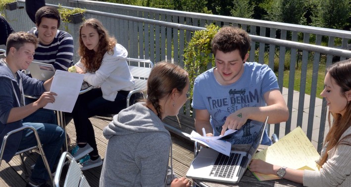 Das Bild zeigt eine Gruppe von Schülern arbeitend an einem runden Tisch.