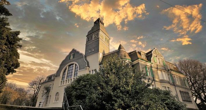 Das Bild zeigt Kunstmuseum Solingen. Ein schlossartiger Bau, der von schräg unten fotografiert wurde. Deer Himmel versinkt schon allmählich in der Abenddämmerung.