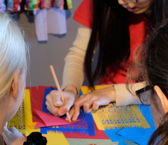 Foto: Konfuzius-Institut Impression Scherenschnitt: Das Bild zeigt eine Mitarbeiter*in, die zwei Schüler*innen anweist.
