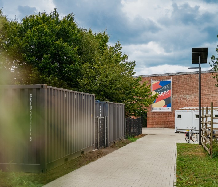 Museumsgebäude mit umgebenden Grünanlagen, 2 Containern und einem WC-Container auf dem Vorplatz.