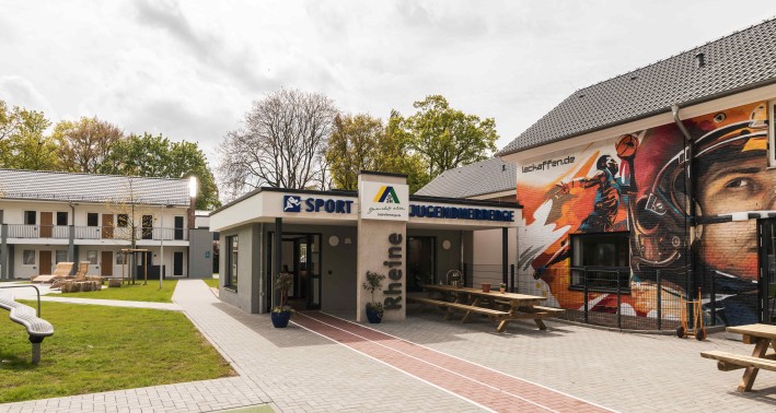 Außengelände der Jugendherberge Rheine mit dem Eingangsbereich und Logo der Jugendherberge