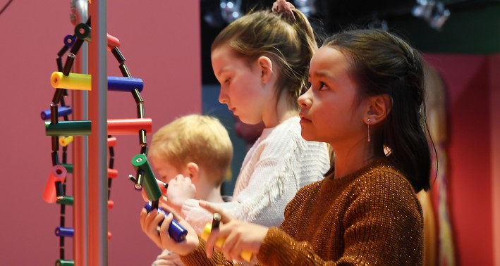 Drei Kinder betrachten ein Ausstellungsstück des Discovery Museums