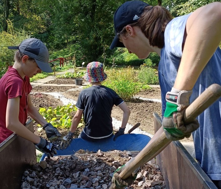 Jugendliche mit Handschuhen und Geräten im Botanischen Garten