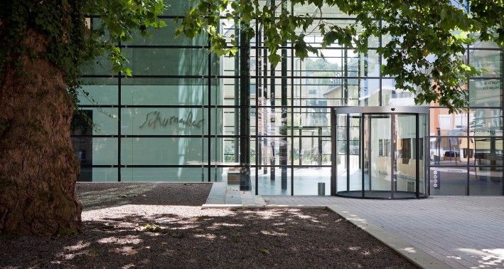 Gebäude mit einer Glasfassade und einem Sichtbetonbau, an dem in Metall-Lettern der Schriftzug 