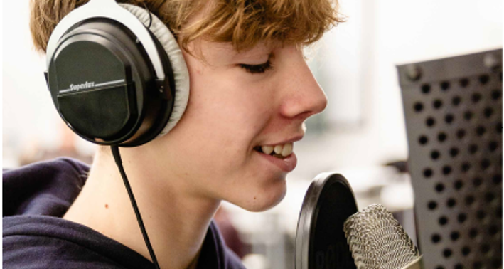Ein Schüler mit Kopfhöreren vor einem Mikrophone-Setup beim Lernort Digital Making Place Nord